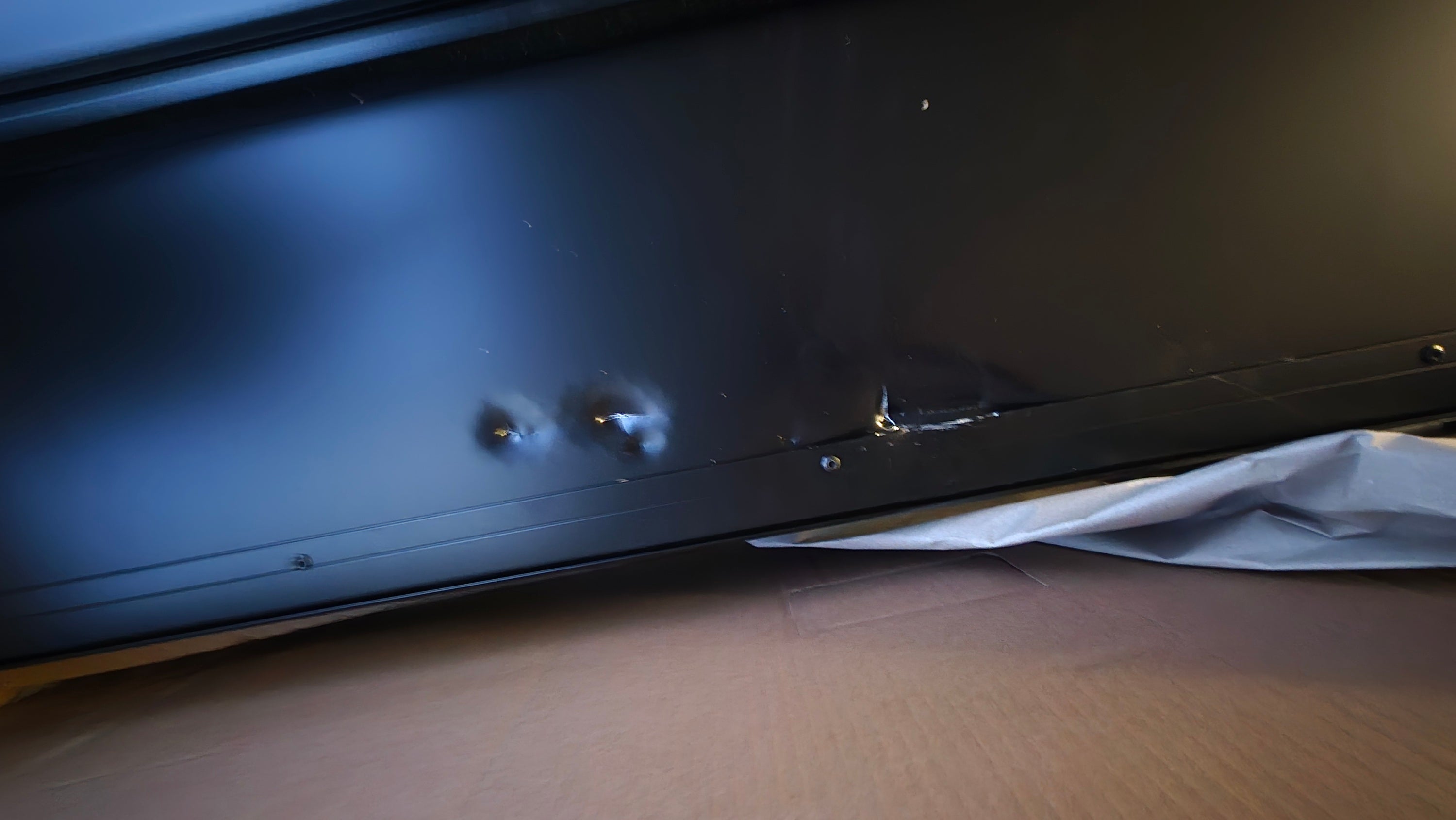 Schwarzer fernseher mit sichtbaren beschädigungen am unteren rand neben dachzelt cumaru light goldbraun