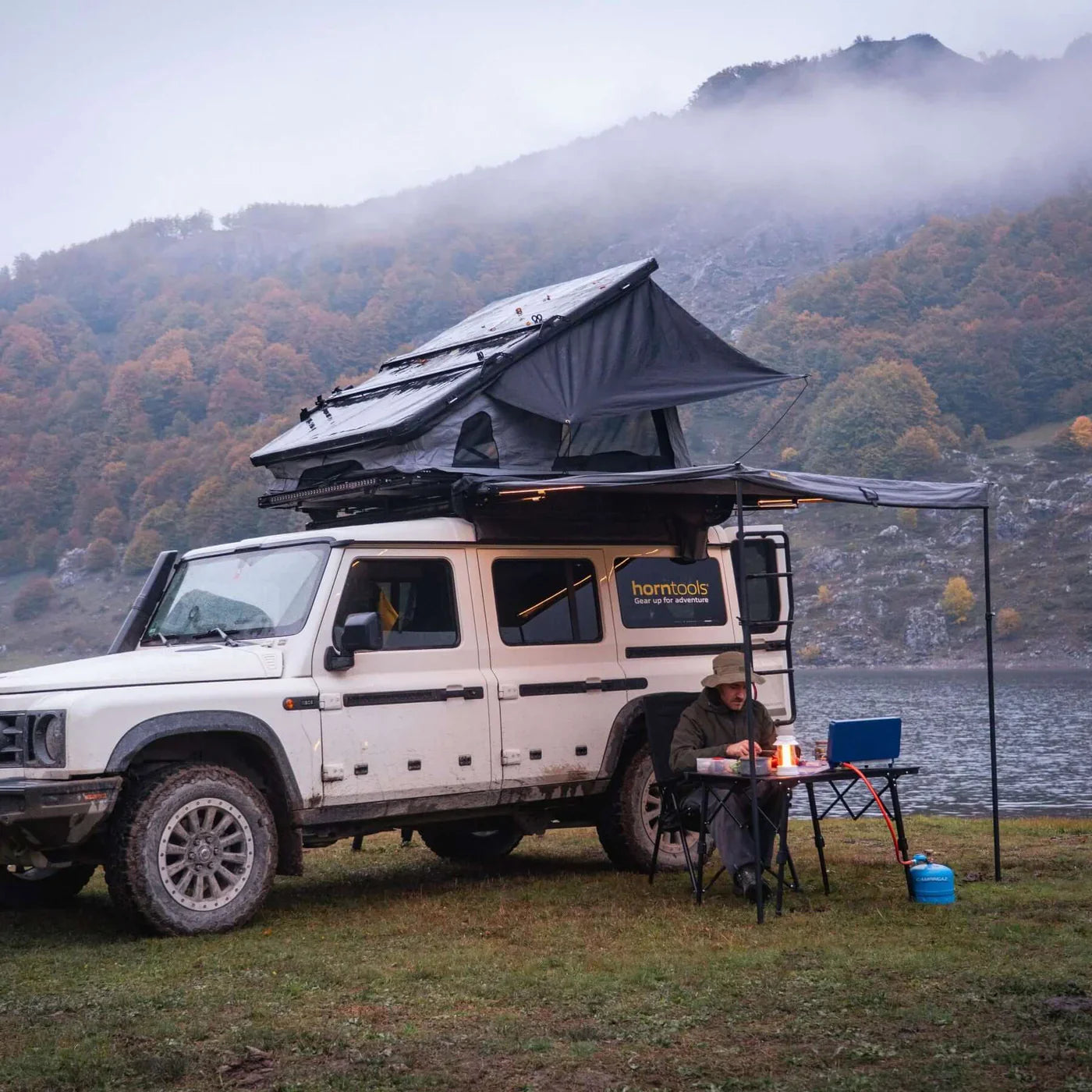 Weißer offroad suv mit horntools campingstuhl recliner und verstellbarer rückenlehne unter schwarzem dachzelt