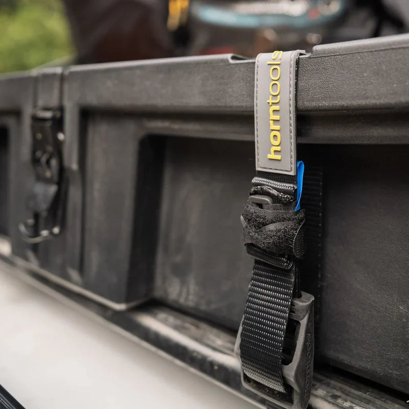 Schwarzer webgurt mit grauem horntools etikett und blauem akzent an dachbox offroad 98 liter horntools transportbox wasserdicht