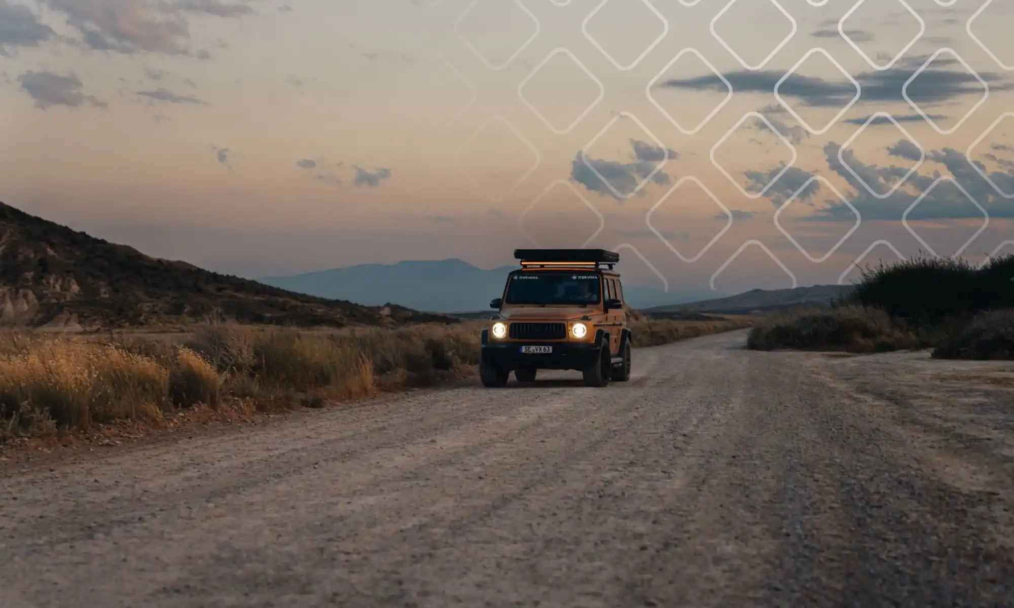 Geländewagen mit Dachgepäckträger, der bei Dämmerung auf einem Schotterweg parkt.