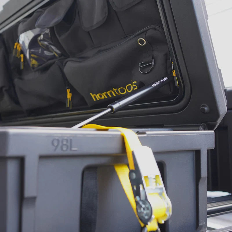 Schwarze horntools transportbox mit gelben zippern und metallschlaufe in grauer dachbox offroad 98 liter wasserdicht